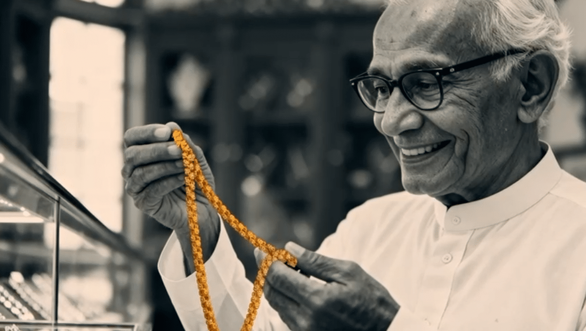 Historic jeweller holding a gold chain in a jewellery showroom
